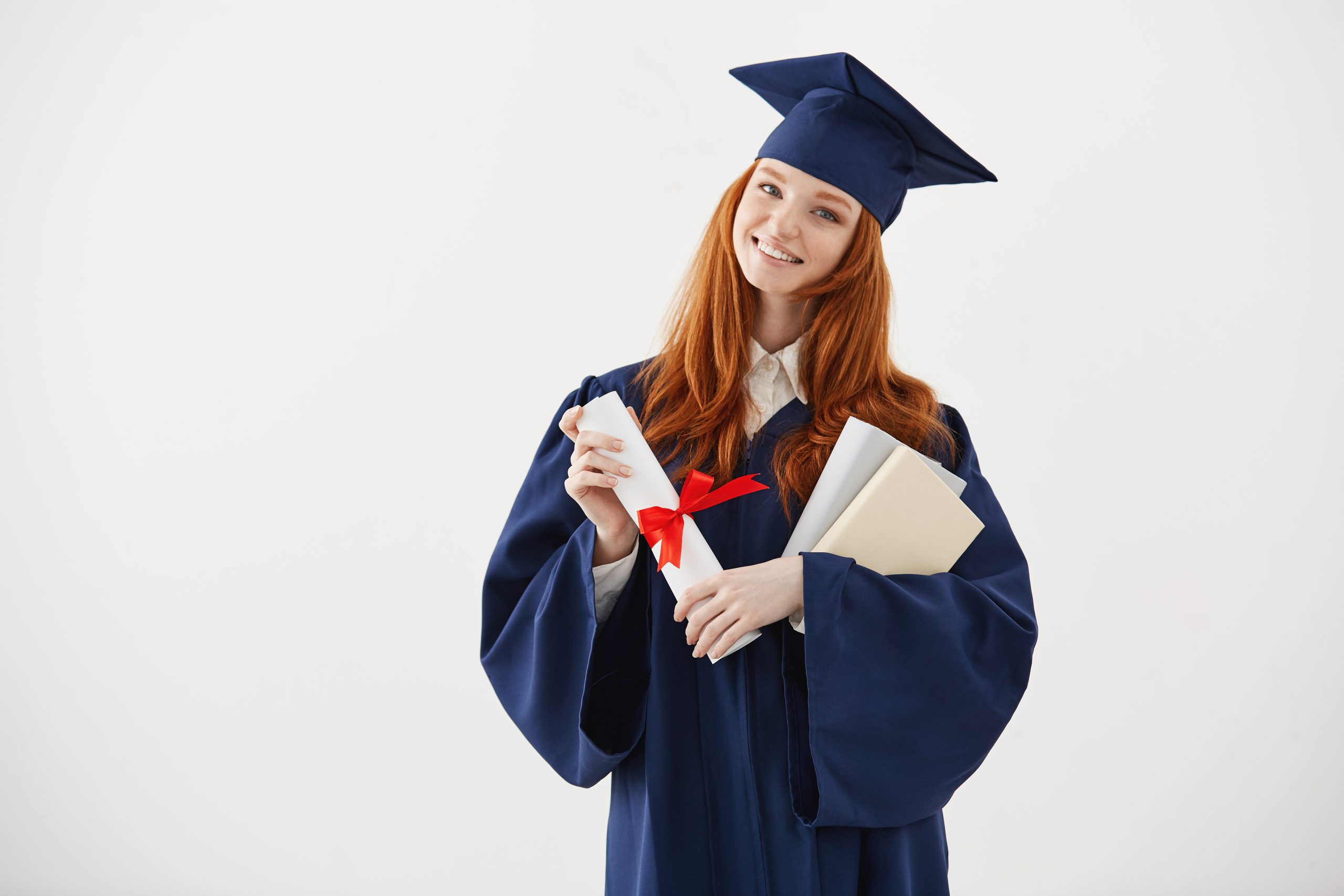 Happy beautiful redhead female graduate smiling holding books and diploma over white background. Copy space.